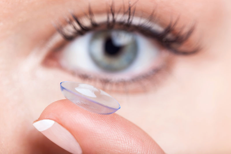 woman holding contact lens on finger